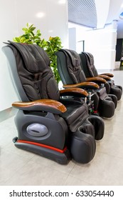 Three black leather comfortable massage chairs in bright light interior. Vertical image 