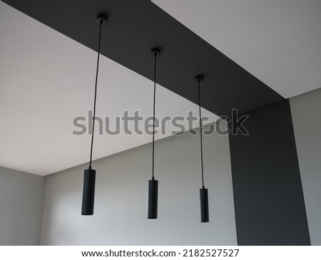 Three black modern bar lights hanged on black ceiling