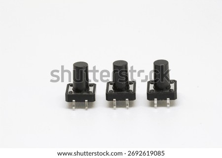 Three black tactile pushbutton switches with tall actuators standing in a row, isolated on white