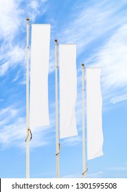 Three blank white flags on flagpoles against cloudy blue sky with perspective, corporate flag mockup to ad logo, text or symbol, company identity flag template with copy space