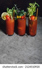 three Bloody Mary cocktails on concrete