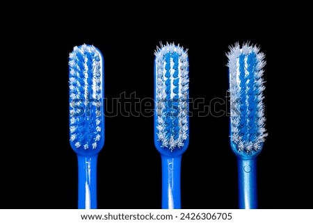 Three blue colored toothbrushes heads isolated in black background. One new with clustered bristles, one used for three months and one used longer with disheveled, bristly and shaggy feather.