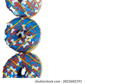 Three blue donuts stacked vertically with yellow drizzle, red sprinkles, and white bone shaped decorations on white background