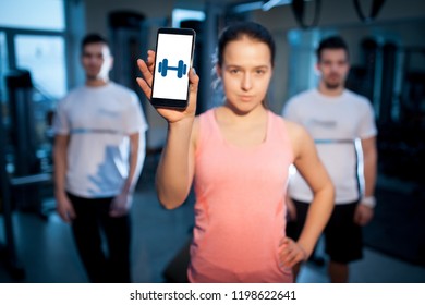 Three Bodybuilders Remote Training With Phone; Fitness People In Gym Have Online Workout;