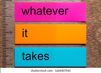 Three bookmark stickers with the words whatever it takes, on a dark natural wooden table