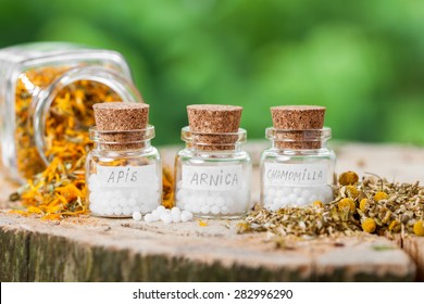 Three bottles of homeopathy globules and healthy herbs.