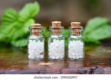 Three bottles of homeopathy globules. Bottles of homeopathic granules. Medicinal herbs on background. Homeopathy medicine concept. 