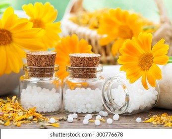 Three bottles of homeopathy globules and marigold flowers.