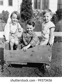 Three boys sitting in a push cart and smiling