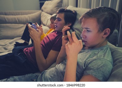 Three Boys Spending Time In A Social Network Using Mobile Phones.  Children With Smartphones At Home. White Kids Using Cell Phones For Gaming. People And Social Media Concept