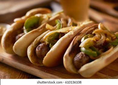 Three Bratwurst Sausages With Grilled Onions And Bell Peppers