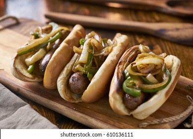 Three Bratwurst Sausages With Grilled Onions And Bell Peppers