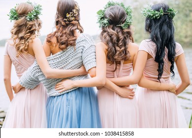 three bridesmaids in powdery dresses transformers and wreaths on the head embrace the bride in a blue dress