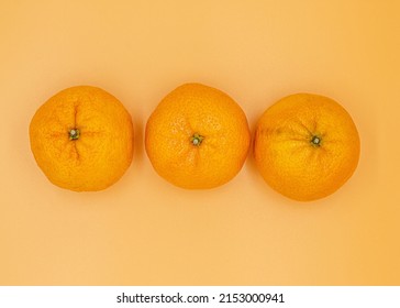 Three Bright Orange Ripe Clementines Overhead View On Monochromatic Orange Background