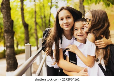 Three brothers hug and are happy on the first day of school. They are on the road leading to the entrance to the school. - Shutterstock ID 2192984161