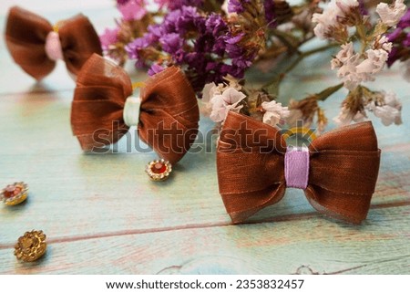 three brown bows lie on a blue wooden table next to a decor of dried flowers. hair accessories . bow. side view