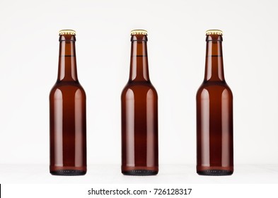 Three brown longneck beer bottle 330ml mock up. Template on white wood table. 