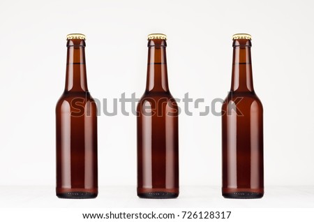Three brown longneck beer bottle 330ml mock up. Template on white wood table. 