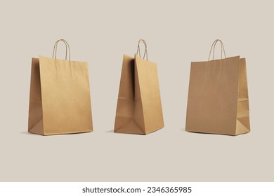 three brown paper shopping bags isolated on beige background, eco-friendly packaging, shopping, delivery concept