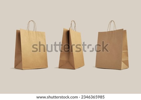 three brown paper shopping bags isolated on beige background, eco-friendly packaging, shopping, delivery concept