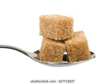 Three Brown Sugar Cubes On Spoon Isolated On White