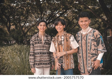 Three buddies in boho style clothing hanging out and posing while at a nature park during a bohemian themed party