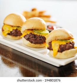 Three Burger Sliders With Cheese And Pickle