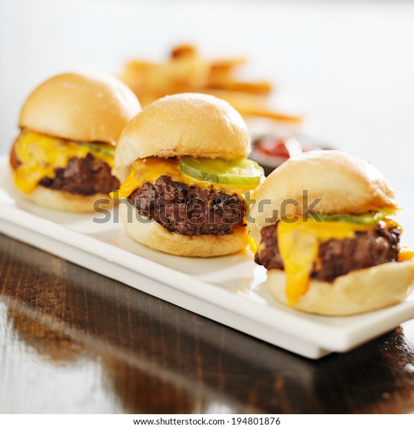 three burger\
sliders with cheese and\
pickle