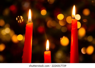 Three burning red candles in the dark against the bokeh of a Christmas tree, lights and decorations. Concept of christmas and new year. - Powered by Shutterstock