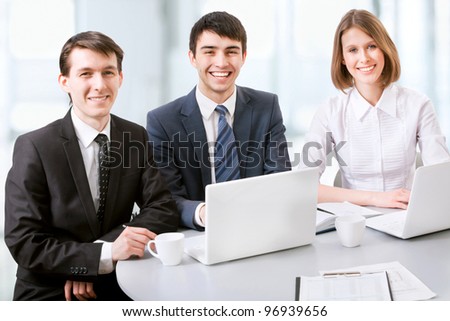 Three business colleagues working together, looking at camera, smiling