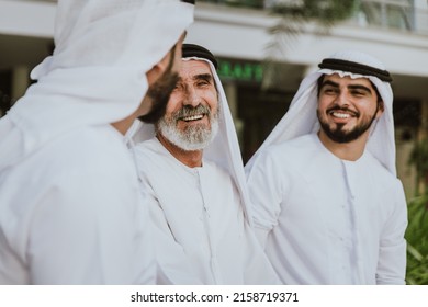 Three Business Men Walking In Dubai Wearing Traditional Emirati Clothes. Different Generation Business People Working Together