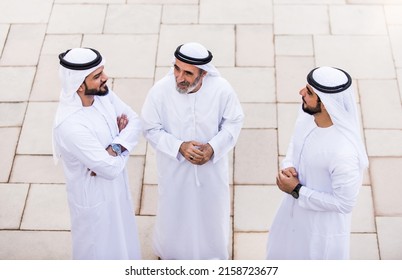 Three Business Men Walking In Dubai Wearing Traditional Emirati Clothes. Different Generation Business People Working Together