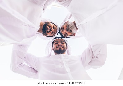 Three Business Men Walking In Dubai Wearing Traditional Emirati Clothes. Different Generation Business People Working Together