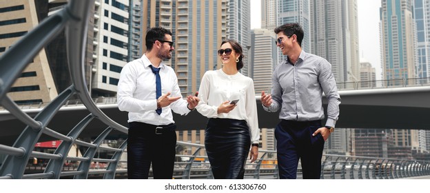 Three Business Partners In Elegant Clothes Walking Down Street Smiling