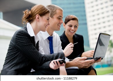 Three Business People Looking At A Laptop Computer