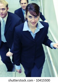 Three Business People Looking Towards Camera And Walking Up Stairs