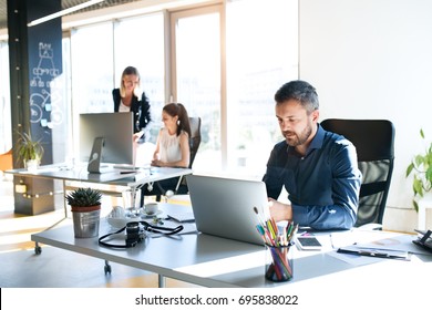 Three business people in the office working together. - Shutterstock ID 695838022