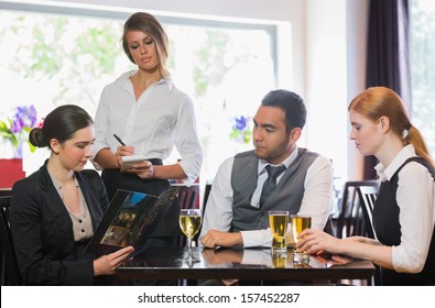 Three business people ordering dinner from waitress in a restaurant