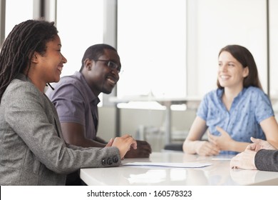 Three Business People Sitting At Conference Table And Discussing During Business Meeting