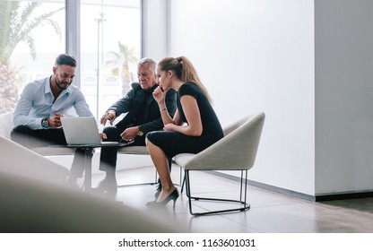 Three Business People Sitting In Office Lobby And Discussing New Project On Laptop. Business Team Working Together On New Project.