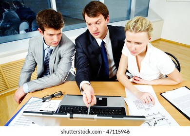 Three Business People Sitting At The Table And Looking Into The Screen Of A Laptop