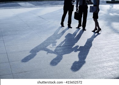 Three Business People Standing Outdoors In Twilight