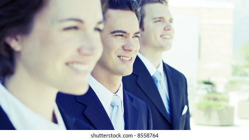 Three Business People Standing In A Row Looking In Same Direction