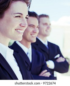 Three Business People Standing In A Row Looking In Same Direction