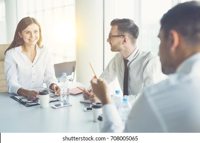 The three business people talk at the table on the sun background