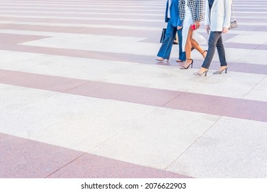 three business women walking across a pedestrian crossing