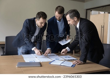 Three businessmen in formal suits negotiating, discuss joint project, working in teamwork, share ideas, review sales statistics, discuss marketing plan, take part in group meeting in conference room 商業照片 © 