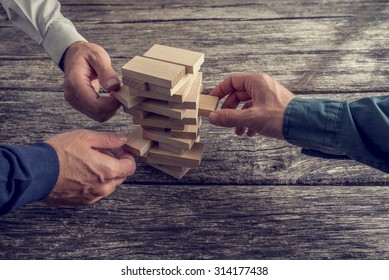 Three Businessmen Hands Playing Wooden Tower Game on Top of a Rustic Wooden Table. Conceptual of Teamwork, Strategy and Vision.
