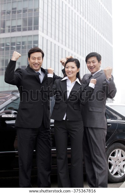 Three businesspeople\
outdoors cheering