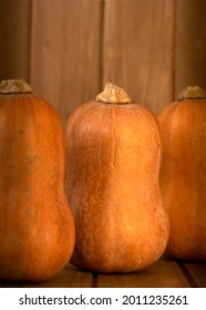 Three butternut squashes lined up with copy-space agasint wooden background- harvest composition